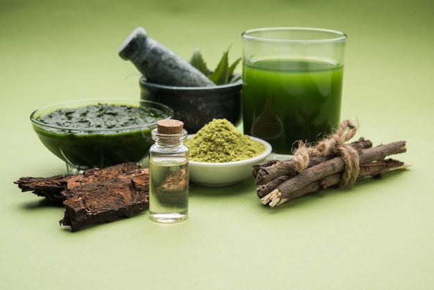 Photo medicinal ayurvedic azadirachta indica or neem leaves in mortar and pestle with neem paste, juice and twigs, powder and oil, selective focus