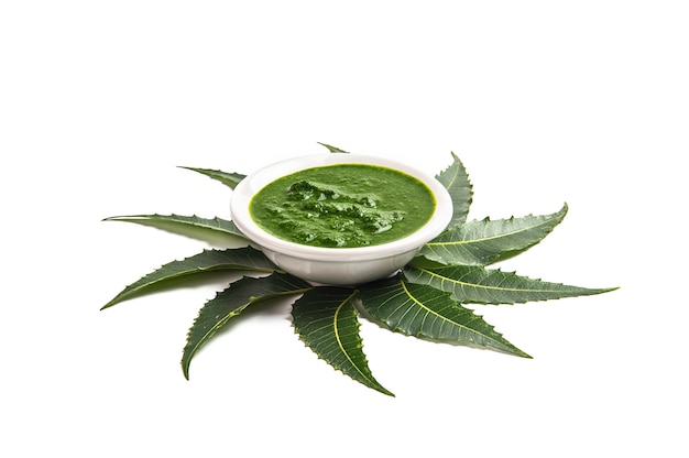 Medicinal Neem leaves with paste in bowl on white background.