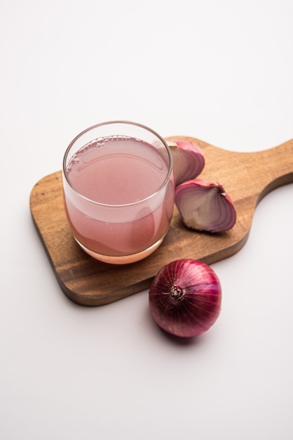 Medicinal Onion juice or syrup in a glass with raw onions. selective focus