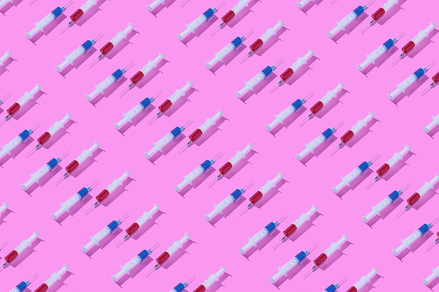 赤と青の薬またはワクチン接種用の血清を満たした使い捨て滅菌注射器からの薬用パターン