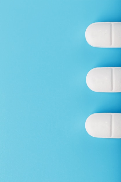 Medicinal tablets in a row on blue