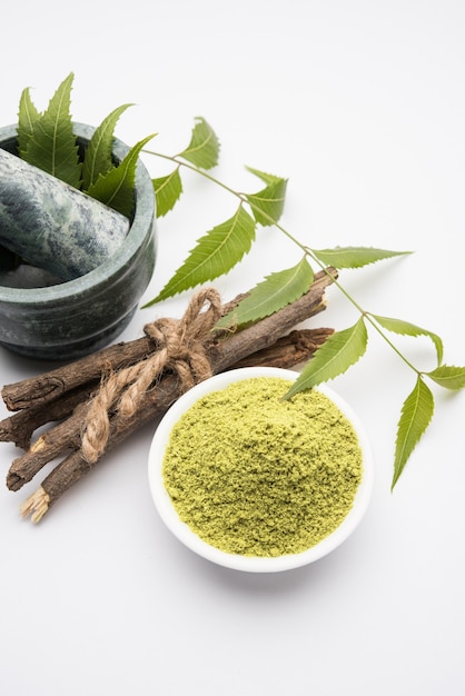 Medicinale Ayurvedische Azadirachta indica of neembladeren in vijzel en stamper met neempasta, sap en twijgen, poeder en olie, selectieve focus