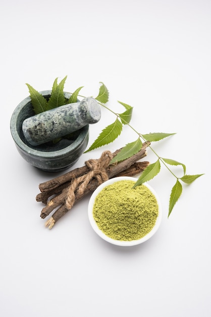 Medicinale Ayurvedische Azadirachta indica of neembladeren in vijzel en stamper met neempasta, sap en twijgen, poeder en olie, selectieve focus