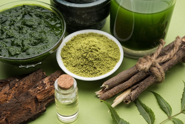 Medicinale Ayurvedische Azadirachta indica of neembladeren in vijzel en stamper met neempasta, sap en twijgen, poeder en olie, selectieve focus