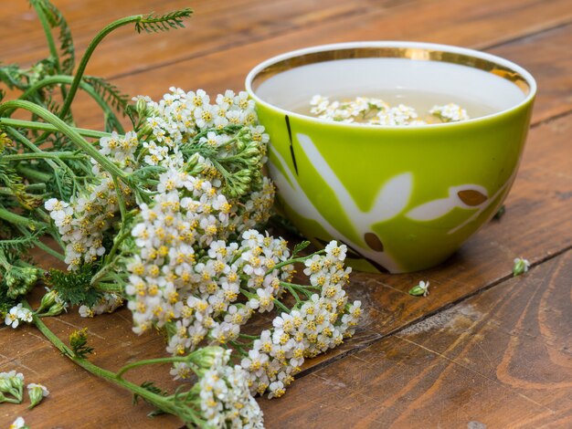 Medicinale plant duizendblad, een mok met een afkooksel van duizendblad bloemen op een houten ondergrond