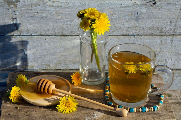 Medicinale thee van paardenbloem in glazen beker met honing paardenbloem tegen een blauwe rustieke houten muur met kopie ruimte