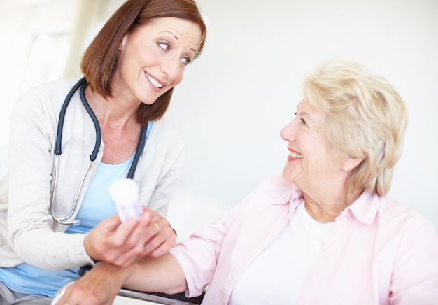 Medicinale verlichting Seniorenzorg Oudere verpleegster en haar oudere vrouwelijke patiënt hebben een discussie over haar medicatie