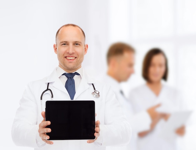 концепция медицины, рекламы и совместной работы - улыбающийся врач-мужчина со стетоскопом, показывающий экран планшетного компьютера над группой медиков
