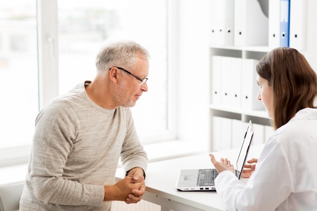 medicine, age, health care and people concept - senior man and doctor with laptop computer meeting in medical office at hospital