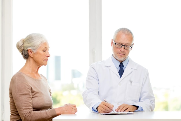 Concetto di medicina, età, assistenza sanitaria e persone - incontro di donna e medico senior in studio medico