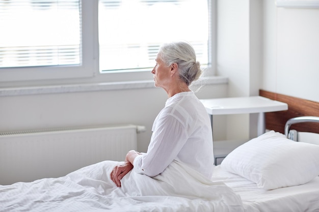 medicine, age, health care and people concept - senior woman patient lying in bed at hospital ward