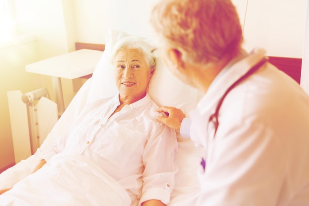 医薬品年齢サポート医療人々のコンセプト - 病院の病棟でベッドに横たわっている高齢の女性を訪問し応援する医師