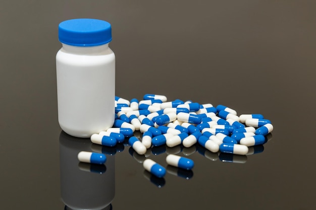 Medicine bottle and pills on black surface Selective focus