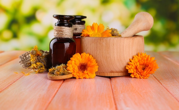 Medicine bottles and calendula flowers on wooden table