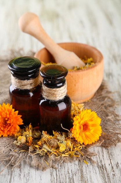 Medicine bottles and calendula flowers on wooden