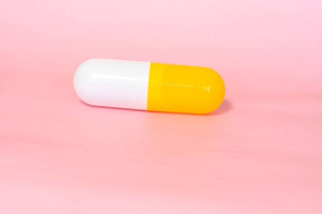 Medicine capsule on pink background close up