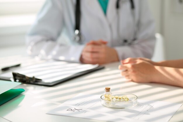 Капсулы и таблетки с лекарствами лежат на фоне врача и пациента