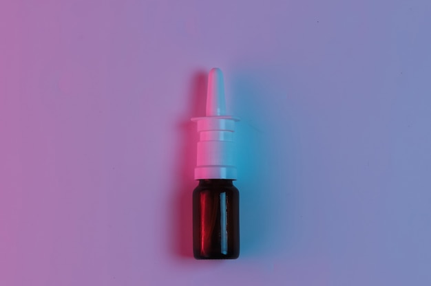 Concetto di medicina. spray nasale con luce notturna blu rosa neon