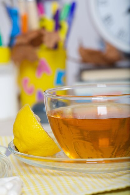 Medicine cup of herbal tea and lemon in front of back to school supplies