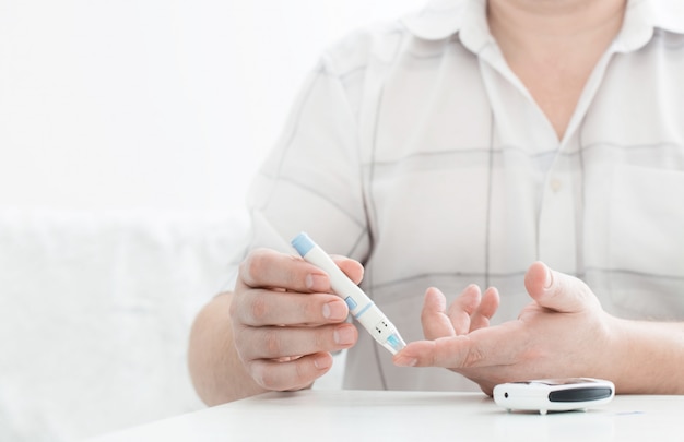 Foto medicina, diabete, glicemia, sanità e concetto della gente - vicino su del dito maschio con la banda di prova