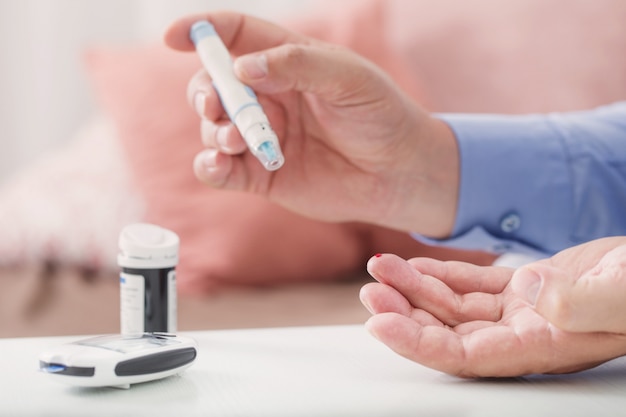 Medicine, diabetes, glycemia, health care and people concept - close up of male finger with test stripe