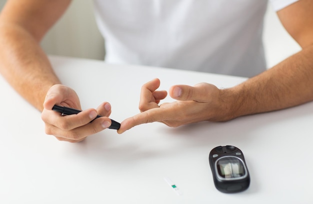 Photo medicine, diabetes, glycemia, health care and people concept - close up of man checking blood sugar level by glucometer at home