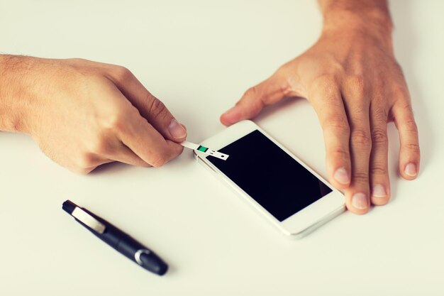 Photo medicine, diabetes, glycemia, health care and people concept - close up of man with smartphone checking blood sugar level by glucometer at home