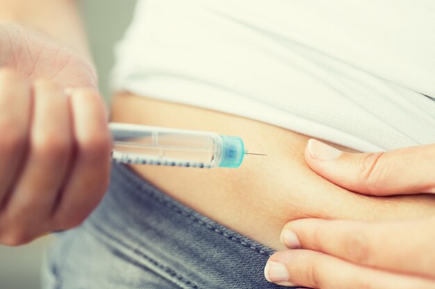 Photo medicine, diabetes, glycemia, health care and people concept - close up of woman hands making injection with insulin pen or syringe