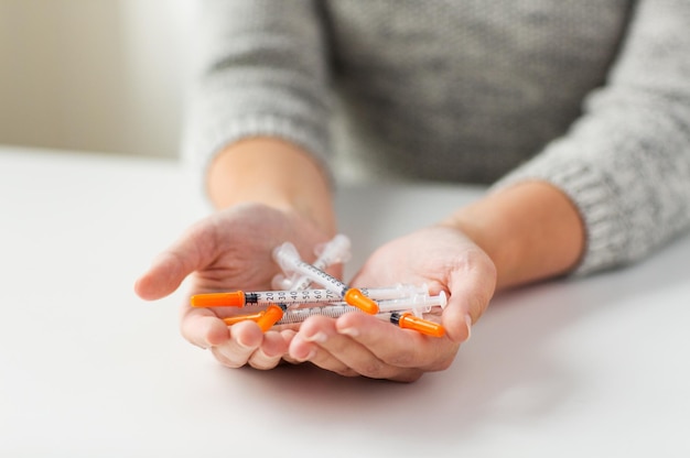 medicine, diabetes, health care and people concept - close up of woman hands holding syringes