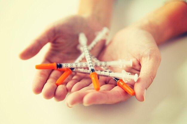 Medicine, diabetes, health care and people concept - close up of woman hands holding syringes