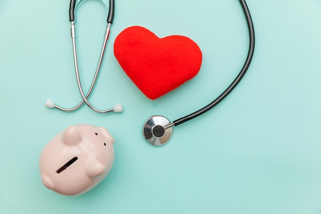 Medicine doctor equipment stethoscope or phonendoscope piggy bank and red heart isolated on trendy pastel blue background