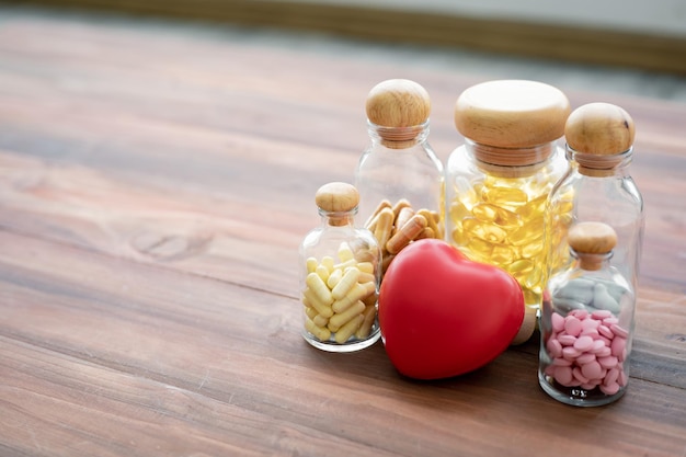 コピースペースと木製の背景にガラス瓶とハートの薬。医学における医学の概念。