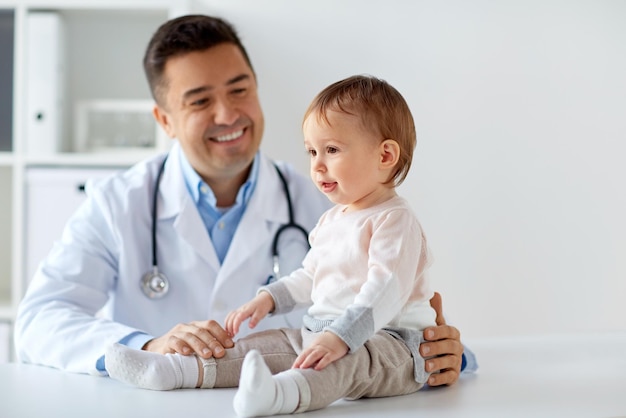 Photo medicine, healtcare, pediatry and people concept - happy doctor or pediatrician holding baby on medical exam at clinic