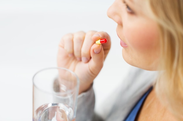 medicine, health care and people concept - close up of woman taking in pill