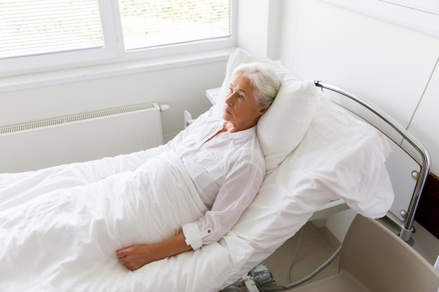 Photo medicine healthcare and old people concept sad senior woman lying on bed at hospital ward