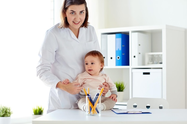 Photo medicine, healthcare, pediatry and people concept - happy doctor or pediatrician holding baby on medical exam at clinic