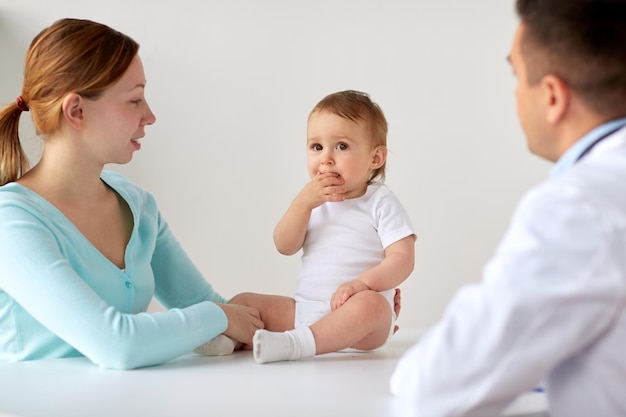 Photo medicine, healthcare, pediatry and people concept - happy woman with baby and doctor at clinic