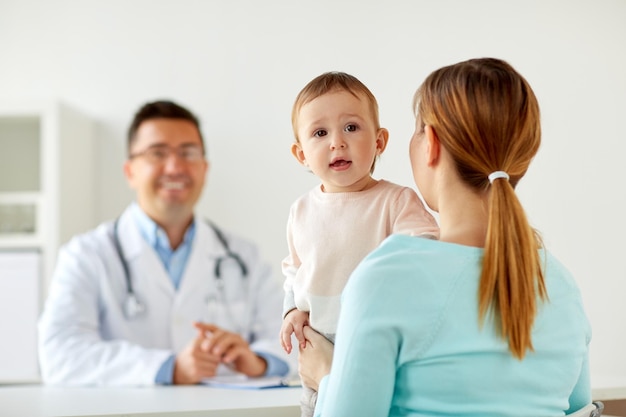 medicine, healthcare, pediatry and people concept - happy woman with baby and doctor at clinic