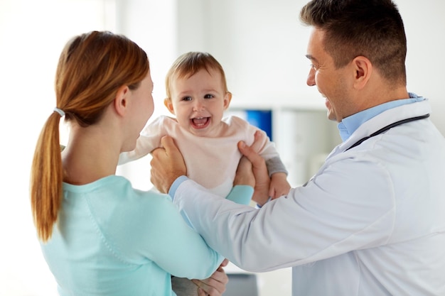 medicine, healthcare, pediatry and people concept - happy woman with baby and doctor at clinic