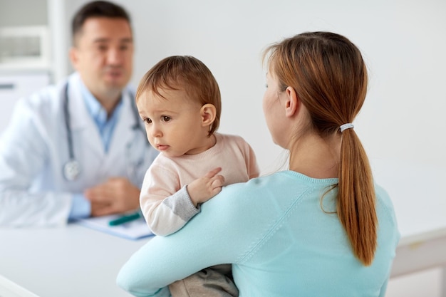 Photo medicine, healthcare, pediatry and people concept - happy woman with baby and doctor at clinic