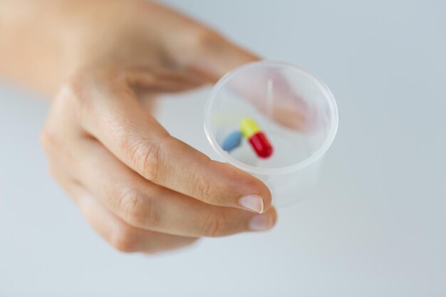 Foto medicina assistenza sanitaria e persone concetto di up vicino di mano femminile che tiene la tazza con le pillole