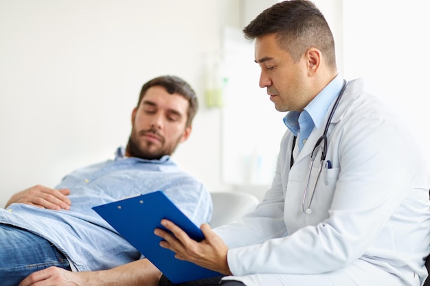 Photo medicine healthcare and people concept doctor with clipboard and young male patient having health problem meeting at hospital