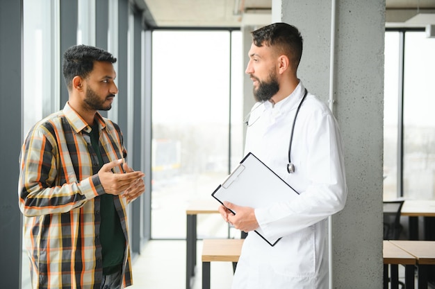 Photo medicine healthcare and people concept happy doctor with clipboard and young male patient meeting at hospital