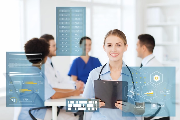 medicine, healthcare, technology and people concept - happy female doctor with clipboard over group of medics meeting at hospital