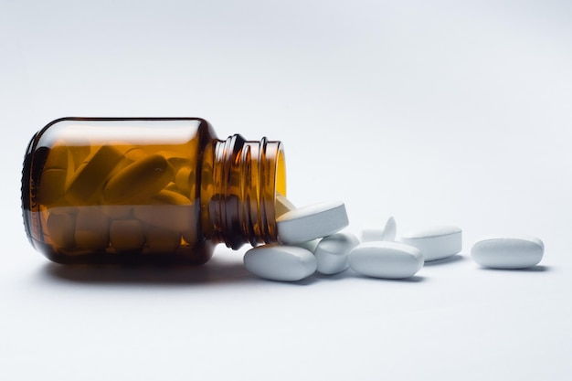 medicine pill tablet with spilled bottle, white background