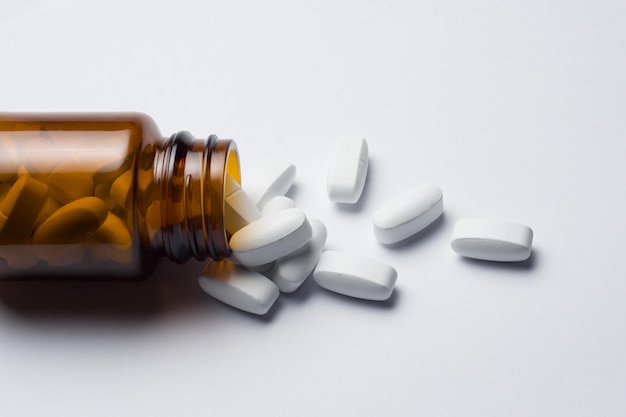 medicine pill tablet with spilled bottle, white background