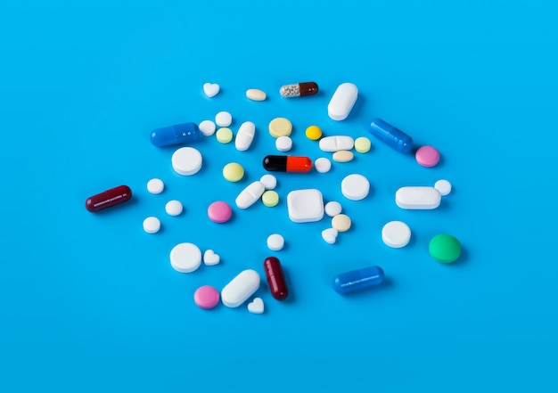 Medicine pills and capsules on blue background