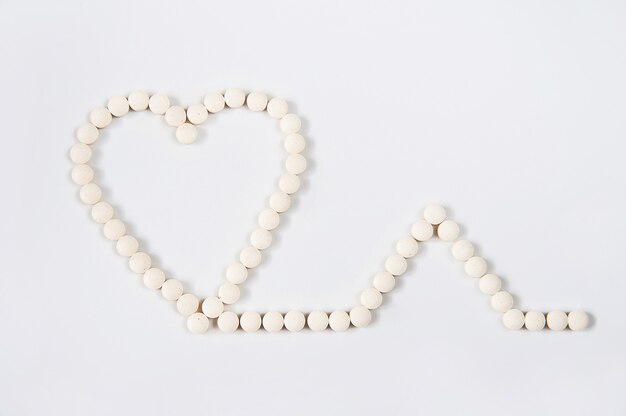 Medicine pills concept on gray background. Round pills in the shape of a heart on a white background