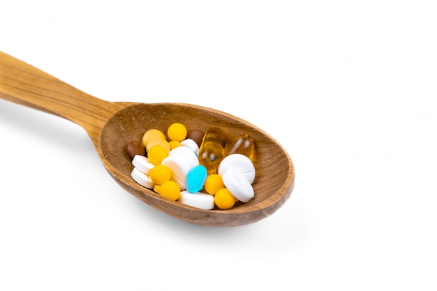 Medicine, pills and drug in wood spoon on white background with copy space