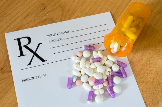 Medicine Pills on Prescription Form on wooden background.